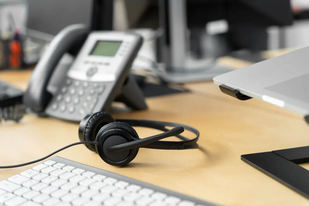 Masa telefonu ve kulaklık bulunan çalışma alanı